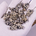 Dalmatian stone angel charms set with metal loops shown on a gloved hand for scale - Spotted Stone