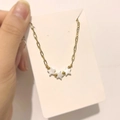 Detailed close-up of three white shell star pendants on a delicate gold link chain - Star Style