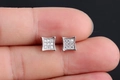 Vue macro de boucles d'oreilles carrées argentées avec zircons AAA tenues entre doigts - Zircon Blanc Plaqué Platine