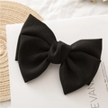 Detail of a large black double-layered knotted bow hair clip on a minimalist white background - Black