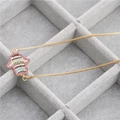 Macro shot of gold Hamsa pendant with colorful zircon stones on gray velvet tray - B0123 Hamsa A Gold