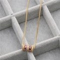 Detail of gold cylinder necklace with purple heart gemstone in grey jewelry tray - Gold/Purple Heart Zircon