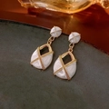 Detailed macro view of vintage gold-plated drop earrings with white marble texture enamel - Silver Earring Post White Marble Pattern Teardrop Earrings