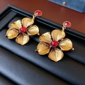 Makroansicht der Vintage-Ohrringe aus Gold mit strukturierten Blüten und roten Edelsteinen - Vintage Goldene Rote Zirkon Blume (Silbernadel)