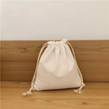 Close-up of minimalist cream cotton linen drawstring bag on a natural wooden table - Small / Beige