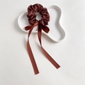 Brown satin scrunchie with long ribbons on a white decorative tray, detail macro view - Red Brown