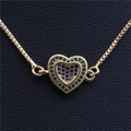 Vue macro du pendentif cœur doré avec zircons bleus et verts sur chaîne vénitienne - Coeur en Or E