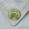 Gros plan d'un badge émaillé grenouille et champignon sur un tissu en jean bleu - Grenouille avec phases de lune (XZ993)
