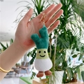 Close-up of cute plush green leek keychain with smiling face and golden metal clasp - Leek Style with Gold Clasp