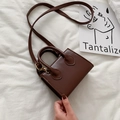 Deep brown glossy mini crossbody bag with gold hardware shown on a white textured background - Dark Brown