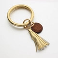 Detail van gouden lederen armband sleutelhanger met PU-kwastje en houten hanger - Goud