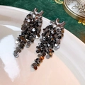 Dettaglio degli orecchini a nappe con paillettes argentate su sfondo di velluto scuro - Nappa di Paillettes Tonde a Forma di U / Nero