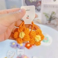 Gros plan d'élastiques à cheveux fleurs orange tricotés main pour filles sur carton - Orange