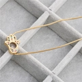 Macro shot of gold Hamsa hand pendant with colorful zircon inlay on a box chain - B0149 Hamsa C Gold