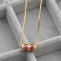 Detailed close-up of a gold cylinder pendant with ruby and diamond in a velvet jewelry box - Gold/Rose Red Heart Zircon