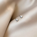 Polished silver heart stud earrings elegantly displayed on champagne silk fabric folds - Steel