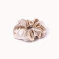 Detailed close-up of glossy champagne satin scrunchie with soft silk texture and pleats - Beige