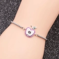 Bracciale in acciaio argento con ciondolo a mela e cristalli rosa su fondo nero - Mela