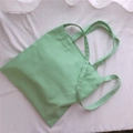 Borsa tote in tela verde chiaro minimalista adagiata su uno sfondo bianco strutturato - Stile a Tre Cinghie (Mano/Tracolla/Spalla) / Verde Menta