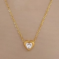Detail of a gold heart pendant necklace featuring a central white zircon on champagne background - Gold