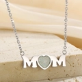 Detalle del collar MOM con ópalo en forma de corazón sobre una superficie de piedra - Plateado (KN233778-KFC)