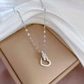 Detailopname van de zilveren hartvormige hanger met Love-gravure op zijden achtergrond - Zilver