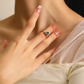 Close-up of a gold ring featuring a sparkling dark blue zircon worn on a woman's finger - Gold Aqua Blue Zirconia