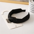 Close-up of a black satin knotted headband with a smooth silky texture on white props - Black