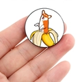 Close-up of circular badge featuring a cartoon Corgi in a banana held by fingers - Corgi in Banana (XZ4708)