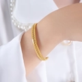 Polished gold cuff bracelet with a twisted rope center detail on a woman's wrist - Z281 - Woven Style / Gold-Woven Texture