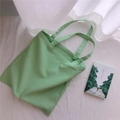 Vista dall'alto della borsa tote in tela verde erba con doppi manici su sfondo in tessuto bianco - Stile a Due Cinghie (Spalla) / Verde Menta