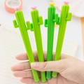 Close-up of green cactus-shaped gel pens with small flower decorations held in hand - Cactus Shape