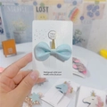 Detail of light blue glitter hair bow featuring a golden unicorn horn on a display card - Light Blue Bow with Gold Horn