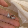 Detailed macro shot of silver huggie earrings with triple row zircon micro-pave setting - Silver Three-Layer Zircon Ear Cuff