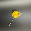 Makroaufnahme einer gelben Satin-Rosen-Anstecknadel mit einem hohlen goldenen Blatt-Accessoire - Gelb