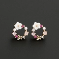 Close-up of pearl flower earrings with butterfly details and colorful zircon stones - Gold