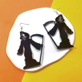 Detail view of black acrylic Grim Reaper earrings on a decorative ceramic tray - Grim Reaper