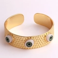 Vue macro d'un bracelet doré réglable avec finition texturée et charmes d'yeux maléfiques - Vert