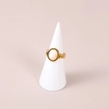 Minimalist gold ring with oval white stone on a white conical display stand - White