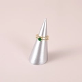 Detail of a gold ring with green gemstone on a silver cone ring display stand - Silver