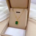 Detailopname van een vierkante smaragd hanger aan een gouden kralenketting in doosje - Titaniumstaal / Goud