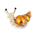 Elegante spilla a chiocciola con smalto arancione e strass bianchi brillanti su sfondo bianco - Oro