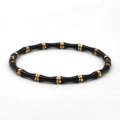 Macro detail of a bamboo shaped titanium steel bangle with black enamel and gold plating - Black