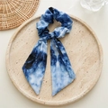Nahaufnahme des blau-weißen Batik-Haargummis mit Schleife auf einem Keramikteller - Hellblauer Zirkon
