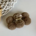 Detail shot of brown plush faux fur pom-poms on a transparent claw clip with gold spring - Brown
