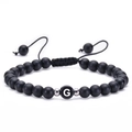 Macro view of 6mm matte black onyx beads with a silver G-letter charm on braided rope - Letter G