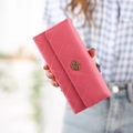 Pink quilted long wallet with golden crown logo in hand-held lifestyle shot - Watermelon red
