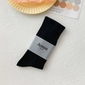 Schwarze mittellange Baumwollsocken mit minimalistischer Papierbanderole auf Sockel - Einheitsgröße / Schwarz