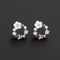 Close-up of floral hoop earrings with pink zircons, shell flower, and pearl on black background - Silver