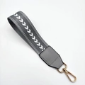 Detail view of a grey woven wristlet strap with white arrow embroidery and gold swivel clasp - Silver Clasp / Gray